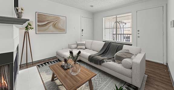 A modern living room with a fireplace on the left and a couch with a blanket on it.