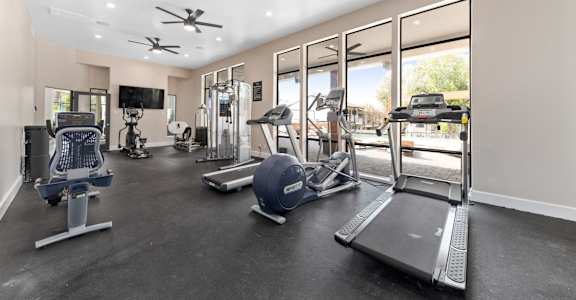 a gym with treadmills and other exercise equipment and windows