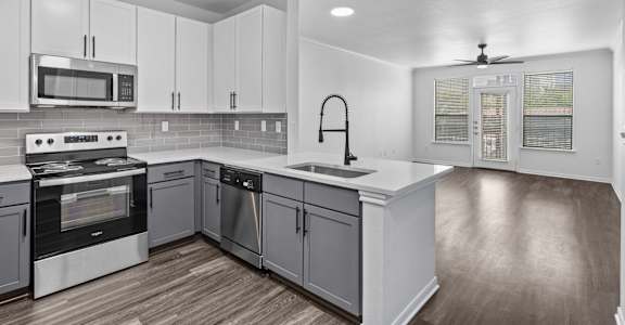 A modern kitchen with white cabinets and a wooden floor.