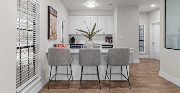 A kitchen with a bar area and two grey chairs.