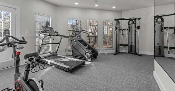 A spacious home gym with a treadmill, stationary bike, and weightlifting equipment.