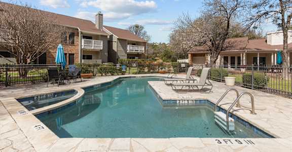 A swimming pool surrounded by a fence and chairs.