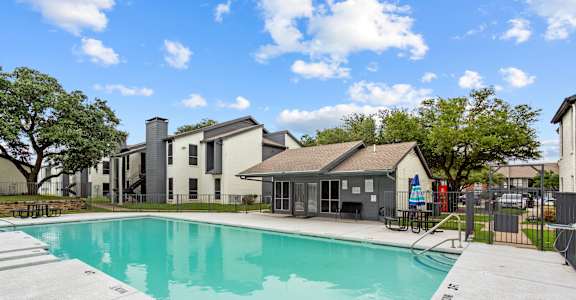 A swimming pool in a sunny day surrounded by buildings.