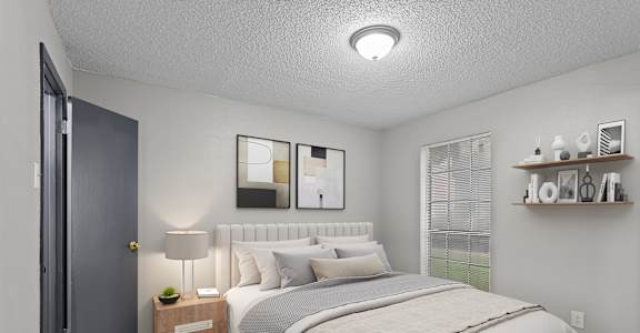 A bedroom with a large bed and a nightstand with a lamp.
