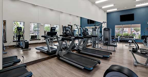 a gym with cardio equipment and weights on a wood floor