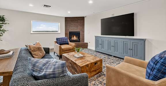 A living room with a grey couch, a wooden coffee table, a fireplace, and a TV on a cabinet.