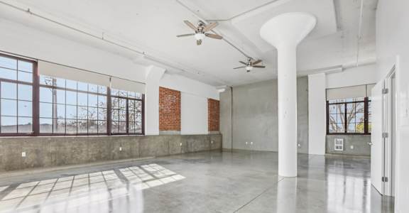 A large empty room with a fan and a window.