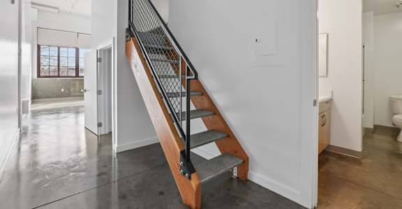 A staircase with a metal railing and wooden steps.