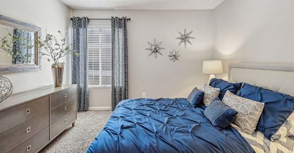 A bedroom with a bed, nightstand, and a dresser.