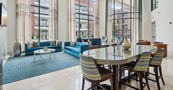 A modern living room with a glass table and blue chairs.