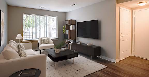 A living room with a white couch, a black television, and a wooden floor.