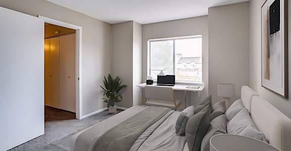 A bedroom with a bed, desk, and chair.