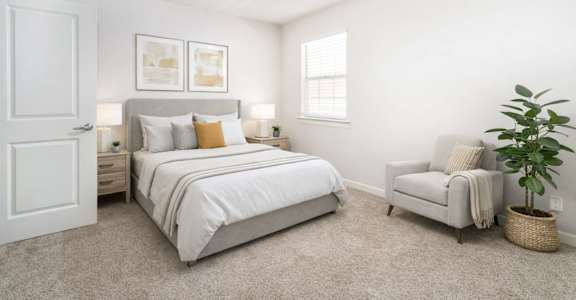 A bedroom with a bed, chair, and ceiling fan.