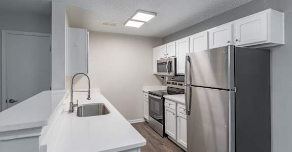 A kitchen with white countertops and stainless steel appliances.