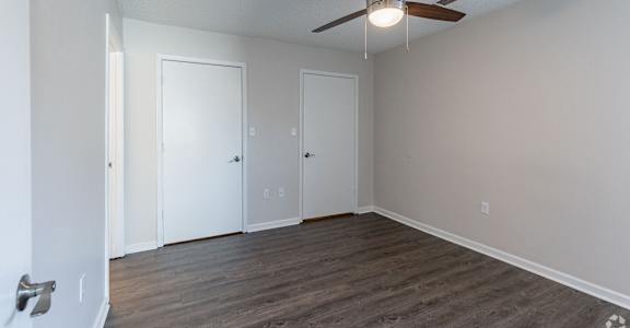 A room with a ceiling fan and three doors.