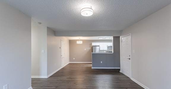 A spacious room with a kitchenette in the background.
