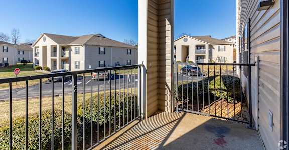 A view from a balcony looking out at a residential area with houses and a clear blue sky.