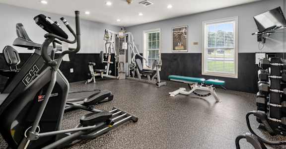 A spacious gym with a variety of equipment including treadmills, weights, and a bench.