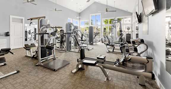 a gym with weights and cardio machines and a tv at The Ridge at Chenal Valley, Little Rock, Arkansas
