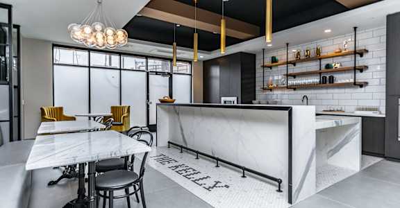 A modern kitchen with a marble island and bar stools.