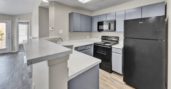 A kitchen with black appliances and a white counter.