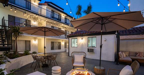 a patio with a fire pit and chairs and umbrellas