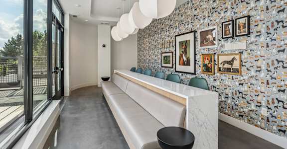 A long white reception desk with a black stool in front of it.