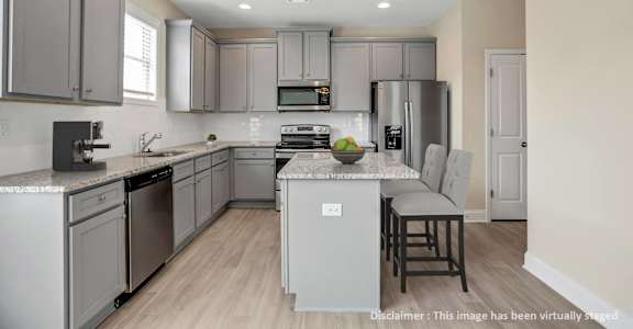 a kitchen with gray cabinets and stainless steel appliances and an island with white counter tops