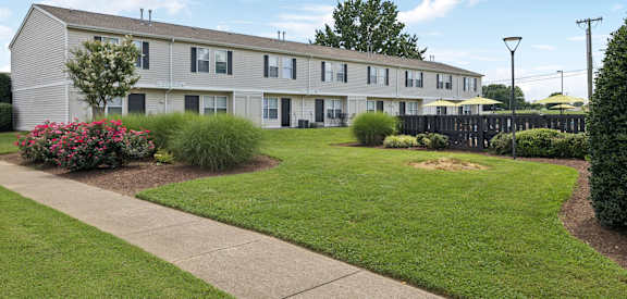 A long building with a grey roof and a green lawn in front.