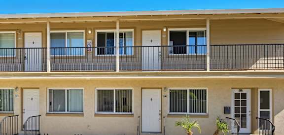A two-story apartment building with balconies and doors.