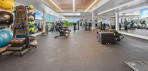 A gym with a variety of equipment and a large mirror on the wall.