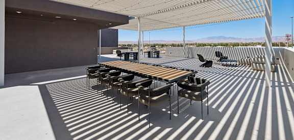 A patio with tables and chairs under a striped awning.