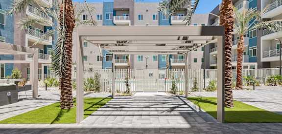 A modern building with a white gate and palm trees in front.