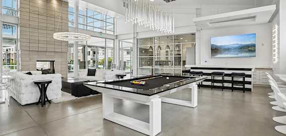 A billiard table is in the middle of a room with a white and black color scheme.