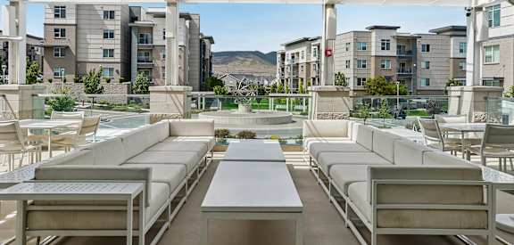 A patio with white furniture and a table is covered by a white roof.