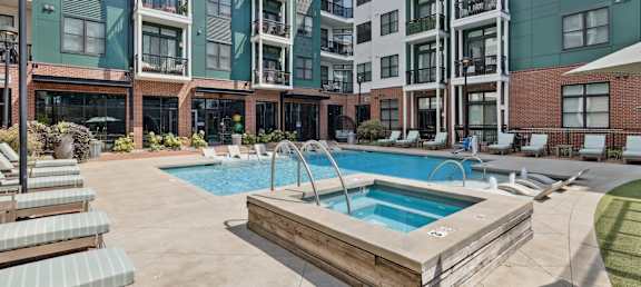 A large outdoor swimming pool with a wooden deck and lounge chairs.