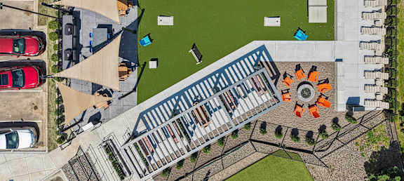 An aerial view of a parking lot with cars and a building with a green lawn in front.