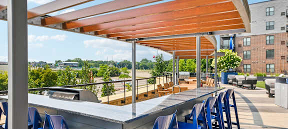 A patio with blue chairs and a wooden table.