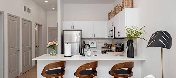 A kitchen with a white countertop and wooden bar stools.at Converge KC Uptown, Missouri, 64111