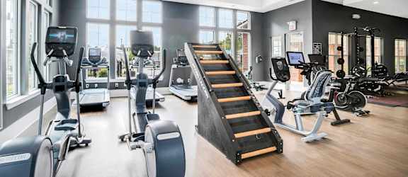 A gym with a variety of equipment including treadmills, stationary bikes, and weight machines.at The Aster Cary, North Carolina