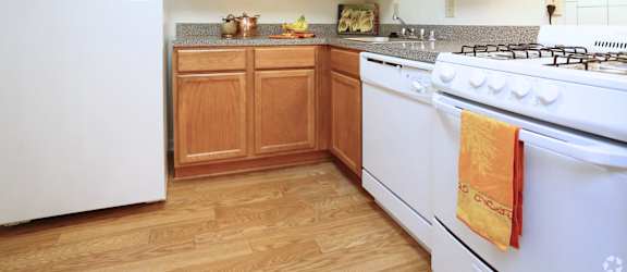 A kitchen with a white stove and wooden cabinets.