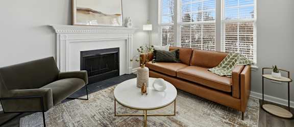 A living room with a fireplace, a couch, a chair, a coffee table, and a painting on the wall.