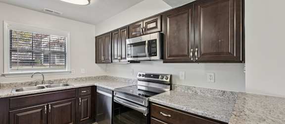 A kitchen with dark wood cabinets and stainless steel appliances.
