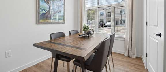 A dining room with a wooden table and chairs.