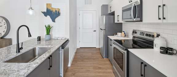 A kitchen with a white counter top and a stainless steel sink.