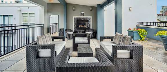 A patio with a black wicker sofa and a fireplace.