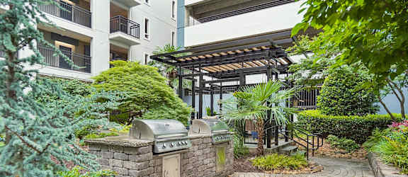 A small garden with a circular brick walkway and a small fountain in the middle.
