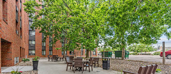 A courtyard with a table and chairs surrounded by trees and buildings.