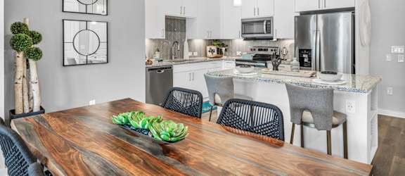 A modern kitchen with a wooden dining table and chairs.