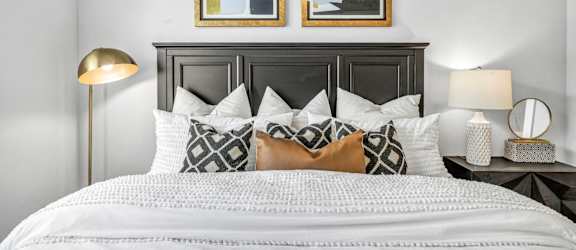 A bed with a white comforter and a black headboard with two framed pictures above it.